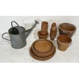 A collection of various terracotta pots and trays along with a galvanised watering can