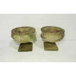 A pair of reconstituted stone garden urns on plinths - diameter 39cm, height 37cm