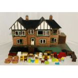 A vintage wooden dolls house, along with a selection of plastic and wooden furniture