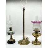 Two vintage oil lamps, one with modern cranberry shade, along with a brass column lamp