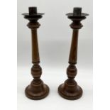 A pair of turned wooden candlesticks - height 46cm