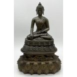 A 17th century Tibetan bronze robed figure of Buddha seated on double lotus base with beaded rim,