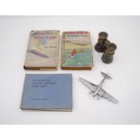 A chrome aeroplane along with various books and a pair of 'Jockey Club, Paris' binoculars