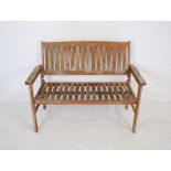 A weathered wooden garden bench with slatted seat - length 120cm