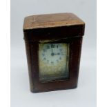 A brass carriage clock with ornate face with gilded decoration, in leather travel case