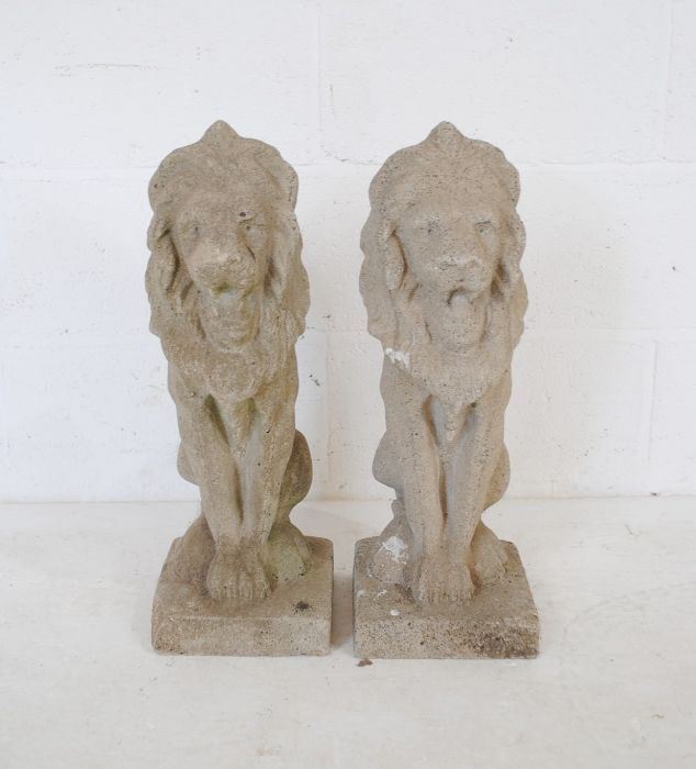 A pair of reconstituted stone garden ornaments in the form of lions - height 56cm