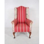 An early 20th century wingback armchair with cabriole legs on turned stretchers.