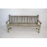 A weathered wooden garden bench with slatted seat - length 180cm