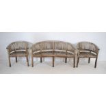 A weathered curved wooden garden bench with two matching chairs