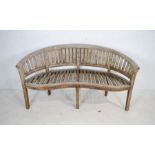 A weathered curved wooden garden bench - length 157cm