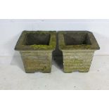 A pair of weathered reconstituted stone garden planters.