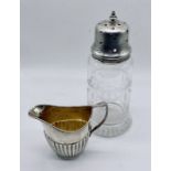 A small hallmarked silver cream jug (64.6g) along with a silver topped sugar caster