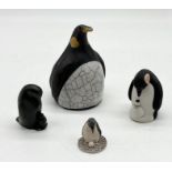 A collection of penguin figures including a larger raku example and three others