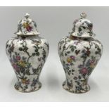A turn of the century pair of lidded urns with transfer printed design showing floral patterns and