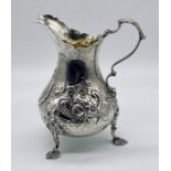 A Victorian silver cream jug with gilded interior, repousse decoration, London 1861, Robert