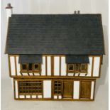 A Tudor style dolls house with slate roof and power source for lighting.