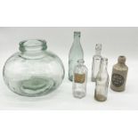 A small glass carboy along with a number of vintage bottles, some named
