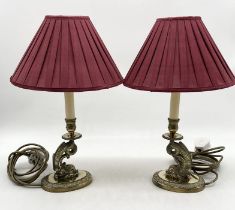 A pair of brass lamps with shades in the form of stylised dolphins