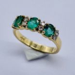 An 18ct gold emerald 3 stone ring set with 8 small diamonds