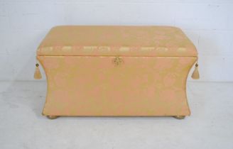 An ottoman with concave sides, upholstered in Chinese silk and raised on flattened bun feet - length