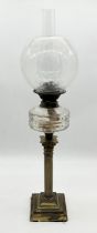An antique oil lamp on brass column base with etched decoration to shade