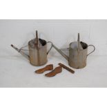 Two galvanised watering cans along with a pair of cast iron shoe lasts