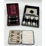 A cased pair of silver plated knife rests along with a set of silver plated spoons etc.