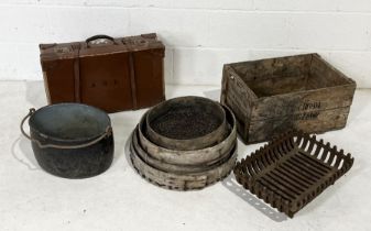 A collection of various items including a vintage leather suitcase, garden sieves, cast iron fire