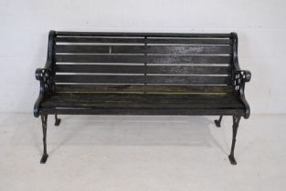 A weathered cast iron garden bench with wooden slatted seat - length 127cm