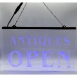 A small light-up neon blue "Antiques Open" sign