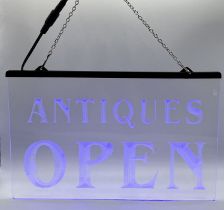A small light-up neon blue "Antiques Open" sign