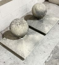 A pair of reconstituted stone gate post finials of spherical form on square plinth bases - 54cm wide