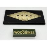 An oak and brass cribbage board decorated with the suits along with a set of Wills Woodbine dominoes