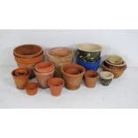 A quantity of various sized terracotta garden pots with some glazed