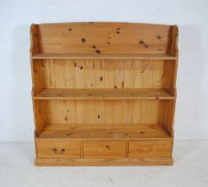 A pine freestanding waterfall bookcase with three drawers under - two handles missing - length