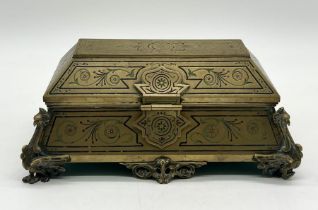 An Egyptian style antique brass casket with griffin feet and inlaid floral detail