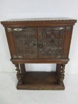 A small oak cabinet with Gothic style carving to doors, the base on barley twist supports, total