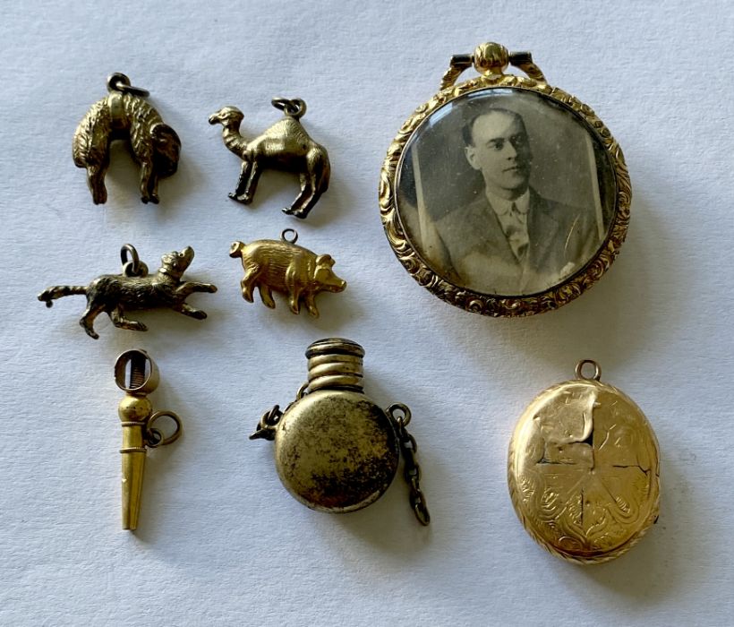 A small collection of yellow metal charms, watch key, photo pendant etc.