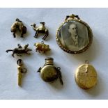 A small collection of yellow metal charms, watch key, photo pendant etc.
