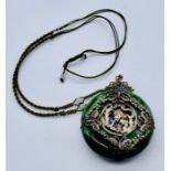 A Japanese green hardstone pendant with SCM decoration of a dragon and pheonix chasing the flaming