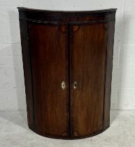 A bow fronted Georgian oak corner cupboard with inlaid detailing.