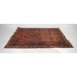 A hand woven red ground Eastern rug, with geometric patterns - 7.5ft x 5.2ft