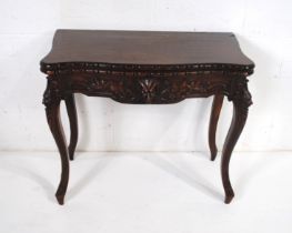 A turn of the century folding oak card table, with carved detailing raised on cabriole legs - length