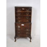 A turn of the century bow-fronted walnut chest of eight drawers, raised on carved cabriole legs -