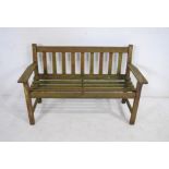 A weathered wooden garden bench with slatted seat - length 128cm