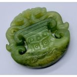 A carved jade pendant depicting dragons, 5.25 cm diameter