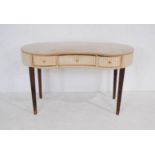 An upholstered kidney shaped dressing table with detachable skirts, with three drawers, raised on