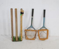 A set of spring loaded cricket stumps on cast iron base, along with a vintage Slazenger tennis