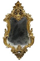 A small carved wooden gilt mirror with distressed glass