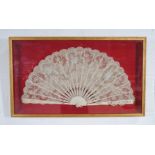 A framed antique fan with bone sticks and lace decoration